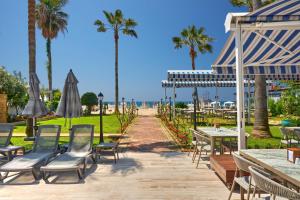 a patio with tables and chairs and palm trees at Elysee Beach Hotel in Alanya