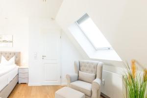 a white living room with a chair and a couch at Himmelreich in Westerland +2 photos