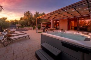 a hot tub on a patio with a table and benches at Olive Spa Oasis with Private Jacuzzi and Summer Kitchen in Orasac