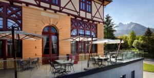 a restaurant with tables and chairs on a balcony at Hotel Lomnica in Tatranská Lomnica