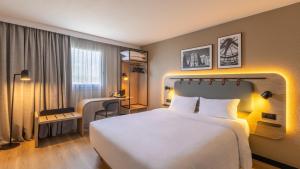 a hotel room with a large white bed and a desk at Campanile PRIME - Le Blanc Mesnil in Le Blanc-Mesnil
