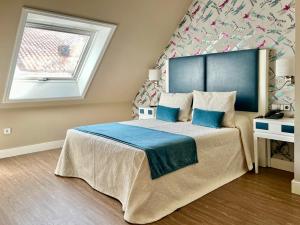 ein Schlafzimmer mit einem großen Bett mit blauer Bettwäsche und einem Fenster in der Unterkunft Hotel Boutique Aquaria Caneliñas in Portonovo