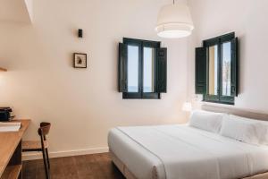 a bedroom with a bed and two windows at La Chipirona Hotel in Valencia