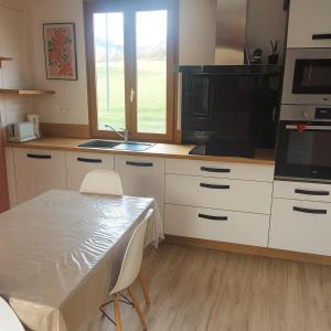 a kitchen with white cabinets and a table with chairs at Le clos du Souffle in Saint-Ouen-sous-Bailly