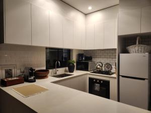a kitchen with white cabinets and a white refrigerator at Bowral Central Garden Apartment in Bowral