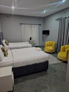 a hotel room with two beds and a yellow chair at Imani Guest House in Bulawayo
