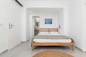 a bedroom with a wooden bed in a white room at Ghjlgolu Suites - Essential Stay in Monte Petrosu