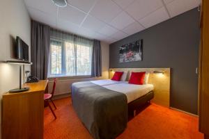 a hotel room with a bed and a desk and a television at Landgoed Mennorode in Elspeet