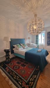 a bedroom with a blue bed and a chandelier at Clos Germanois entre Clermont, Lyon ,St Etienne A89 sortie 32 in Saint-Germain-Laval