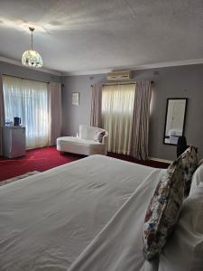 a bedroom with a large white bed and a couch at Imani Guest House in Bulawayo