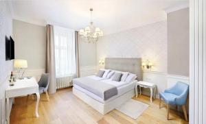 a white bedroom with a bed and a table and chairs at Hotel Lomnica in Tatranská Lomnica