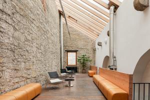 a room with a stone wall and a couch and chairs at Zámecký Hotel Litomyšl in Litomyšl