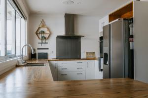 a kitchen with a stainless steel refrigerator and wooden floors at Marsden Manor - Spacious house with large pool in Greymouth