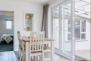 a white dining room with a table and chairs at Marsden Manor - Spacious house with large pool in Greymouth +18 photos