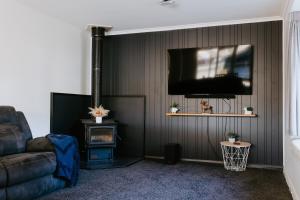 a living room with a couch and a flat screen tv at Marsden Manor - Spacious house with large pool in Greymouth