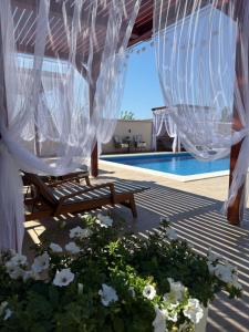 acovered patio with a bench and a pool with white flowers at Vila Gracija in Arandelovac