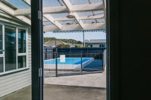 a view of a swimming pool through a glass door at Marsden Manor - Spacious house with large pool in Greymouth