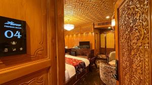 a room with a bed and a desk and a television at Suroor Houseboat in Srinagar