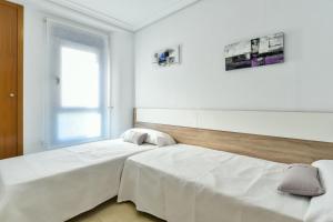 two beds in a white room with a window at Gala Centro Modern I in Torrevieja