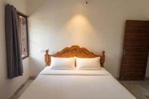 a bed with a wooden headboard in a bedroom at Kattil Madurai in Madurai +6 photos