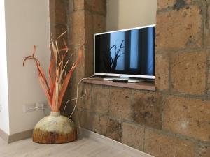 uma televisão sentada numa parede de tijolos com um vaso em Appartamento Malabranca em Orvieto