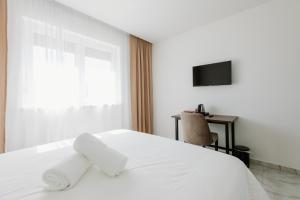 ein Schlafzimmer mit einem weißen Bett und einem Fernseher in der Unterkunft Rustikana doo in Livno