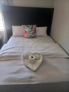 a white bed with a heart shaped towel with a toilet paper at Tourist Guest House Accommodation in Mahikeng