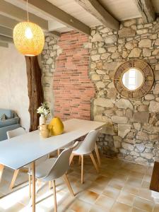 a dining room with a table and chairs and a brick wall at Le Logis de la Forge-10min puydufou in Mortagne-sur-Sèvre