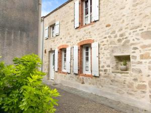 a brick building with white windows and a potted plant at Le Logis de la Forge-10min puydufou in Mortagne-sur-Sèvre