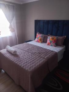 a bedroom with a bed with a blue headboard and pillows at Tourist Guest House Accommodation in Mahikeng