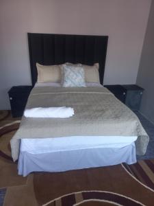 a bedroom with a large bed with a black headboard at Tourist Guest House Accommodation in Mahikeng