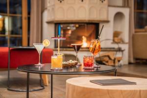 a table with four drinks on it in a room with a fireplace at Swiss Alpine Hotel Allalin in Zermatt