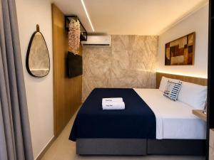 a small bedroom with a bed and a mirror at Emunah Flat Luxo Cabedelo • Piscina no Rooftop in Cabedelo +19 photos