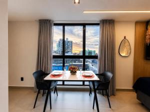 a dining room with a table and chairs and a large window at Emunah Flat Luxo Cabedelo • Piscina no Rooftop in Cabedelo
