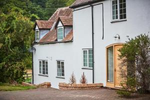 a white house with a wooden door at Lower Tundridge Cottage in Worcester