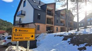a yellow sign in the snow in front of a building at Apartman Eden Divčibare in Divčibare