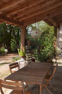 a wooden table and chairs under a wooden pergola at La ferme des Perdilles in Biran