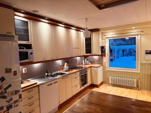 a kitchen with white cabinets and a window at Red House at Kuusitie in Kittilä