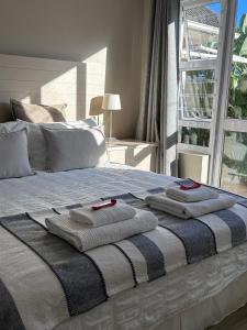 a bed with towels on top of it with a window at The Cottage on Alphen in Heathfield