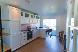 a kitchen with white cabinets and a table and chairs at Hidden Gem Townhouse - Cahersiveen in Cahersiveen +9 photos