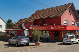 two cars parked in front of a red building at Haven Sierentz in Sierentz