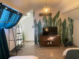 a room with a tv and a mural of leaves at Le gîte des Romains in Anor