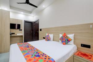 a bedroom with a large white bed with colorful pillows at FabHotel Shivangan in Vrindāvan