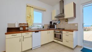 a kitchen with white cabinets and a large window at House Vissum by Villas Guide in Lukovo