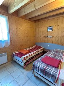 two beds in a room with wooden walls at Gîte EAU'DER in Giffaumont-Champaubert
