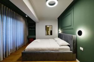 a bed in a bedroom with a green wall at Unique by UpTown Apartments in Iaşi
