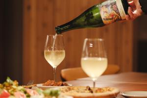 a person pouring a bottle of wine into two wine glasses at Alternest Kamakura in Kamakura
