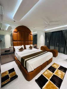 a bedroom with a large bed with a large wooden headboard at Hotel Pacific Regency in Ahmedabad