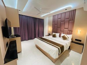a bedroom with a large bed and a television at Hotel Pacific Regency in Ahmedabad
