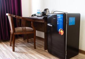 a black refrigerator next to a desk with a chair at Tourist inn Tashkent in Toshkent-Passajir Bekati